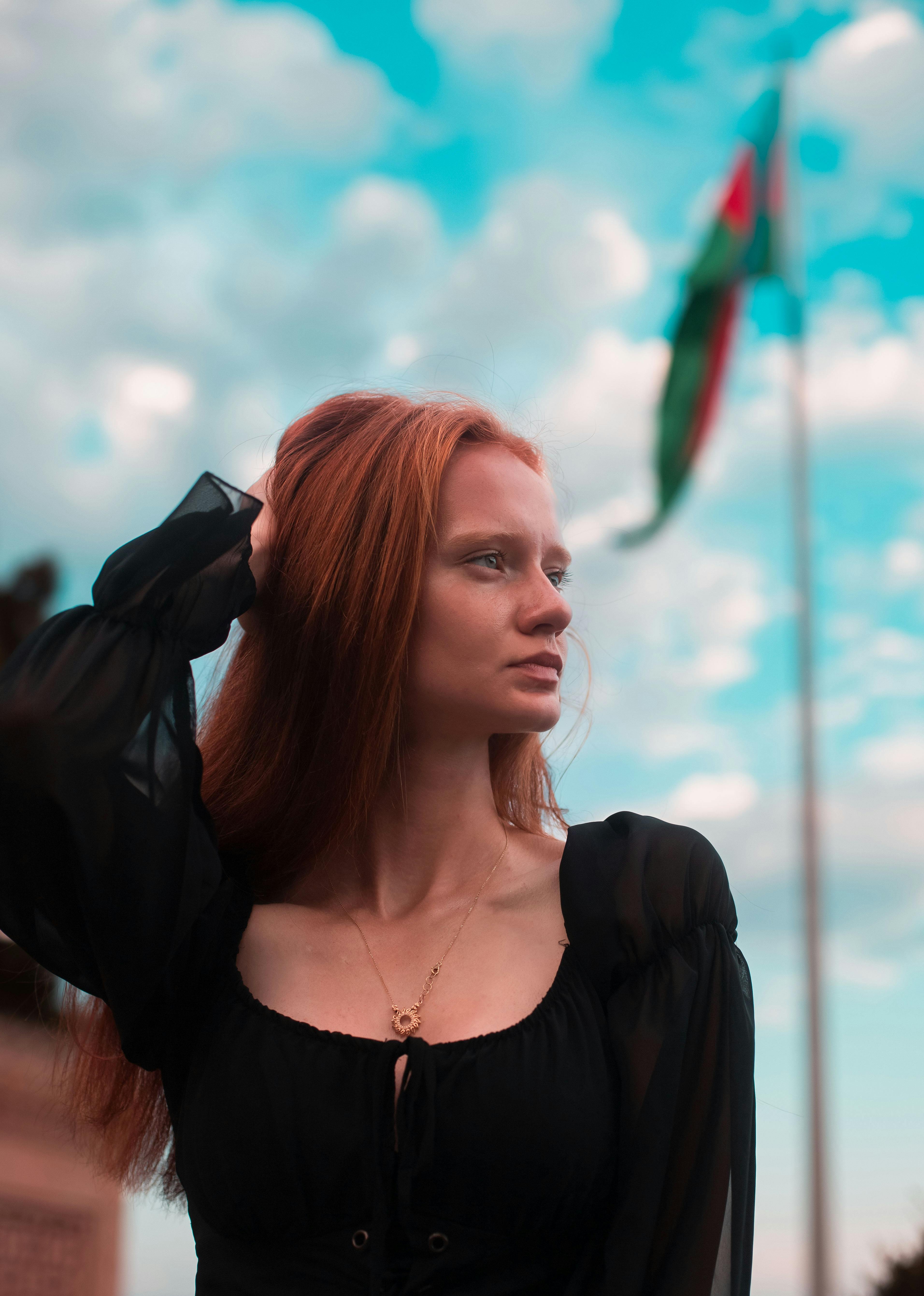 Captivating portrait of a young woman in Baku gazing thoughtfully under a vibrant sky.