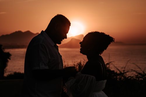 Free A silhouette of a couple sharing a romantic moment during sunset by the beach. Stock Photo