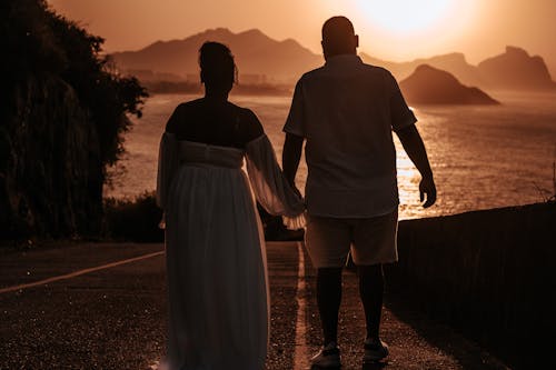 Back View of Couple Holding Hands at Sunset