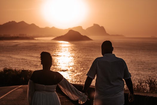 A couple walks hand in hand, enjoying a romantic sunset by the sea in Rio de Janeiro, Brazil.