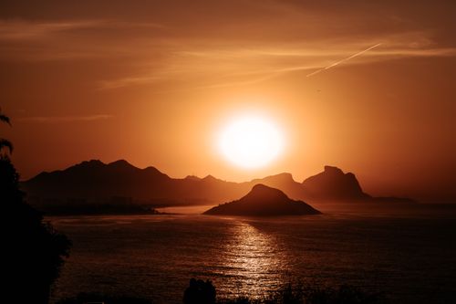 Free Stunning sunset view over the coastal hills and sea at Mesquita, Brazil. Stock Photo