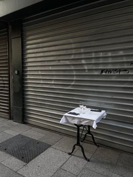 A lone table set against a shutter door in a city street, evoking mystery and urban vibe.
