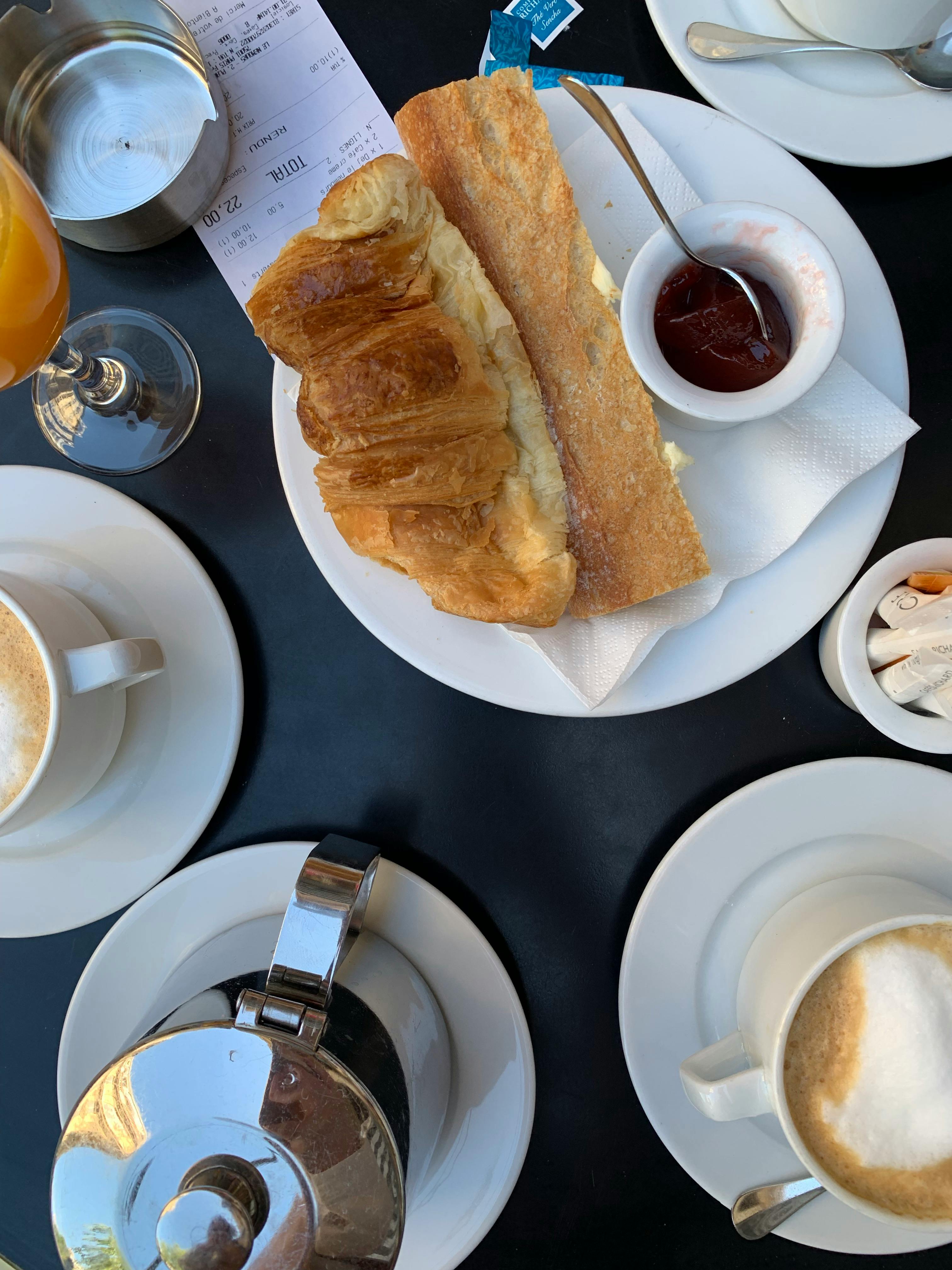 Top view of a classic French breakfast with croissant, baguette and coffee, enhancing a cozy morning vibe.