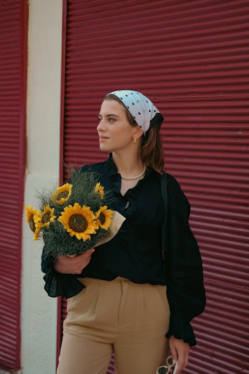 Young Woman Standing Outside and Holding a Bouquet of Sunflowers
