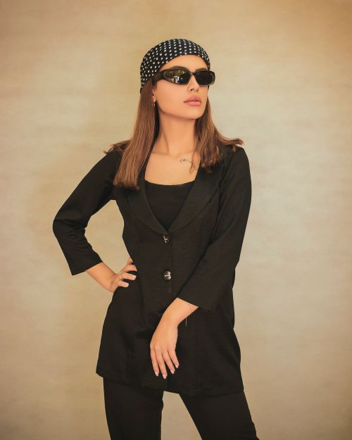 Free Fashion portrait of a woman in a black suit and sunglasses with a stylish headscarf against a neutral background. Stock Photo