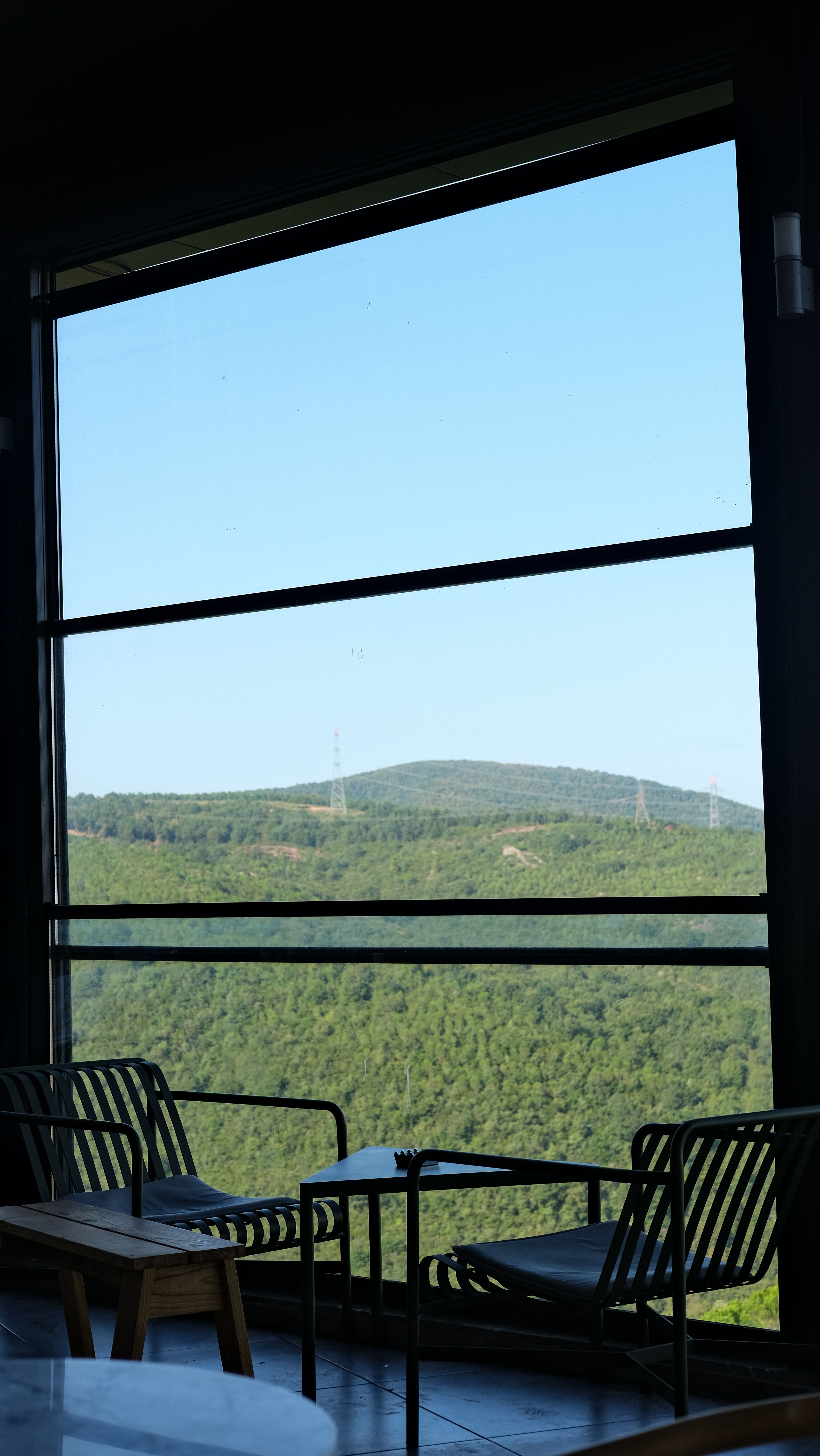 Scenic view from a cozy café window overlooking lush green hills.