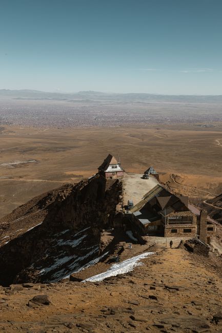 A scenic view of a remote mountainous settlement against a vast horizon, showcasing rugged terrain and vast open skies.
