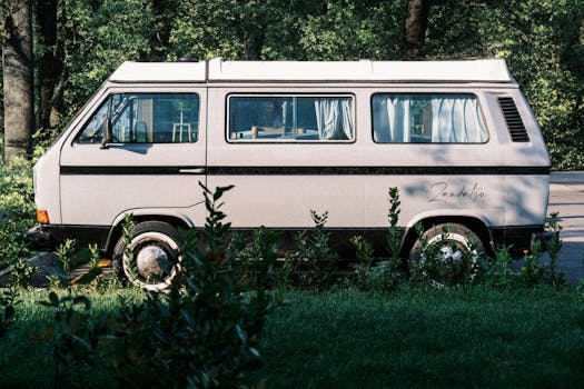 Side view of a classic camper van parked in a lush green setting, evoking adventure and travel nostalgia.