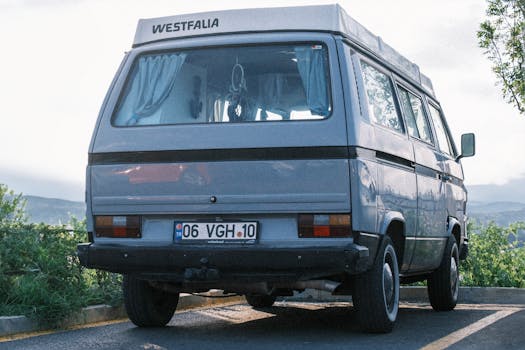 Vintage Westfalia camper van parked in a scenic outdoor area with lush greenery and hills.