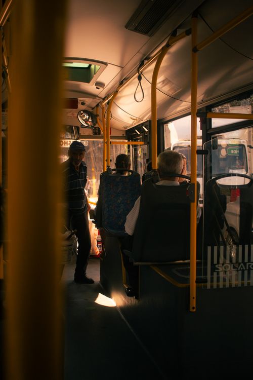 Free Candid capture inside a city bus with passengers traveling through urban streets in warm lighting. Stock Photo
