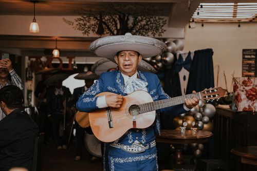 Free A Mexican musician in traditional clothing plays guitar at an indoor celebration. Stock Photo