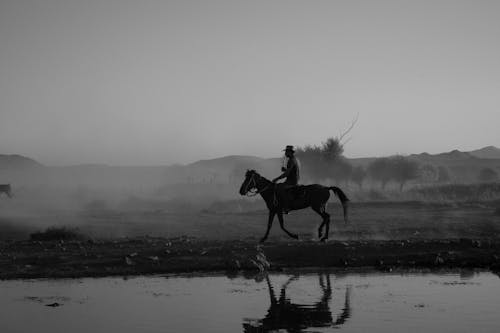 Black and White Photo of a Man Riding a Horse