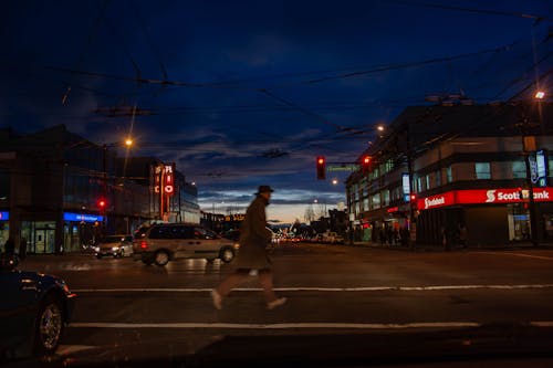 Pedestrian Crossing the Street in a City at Night