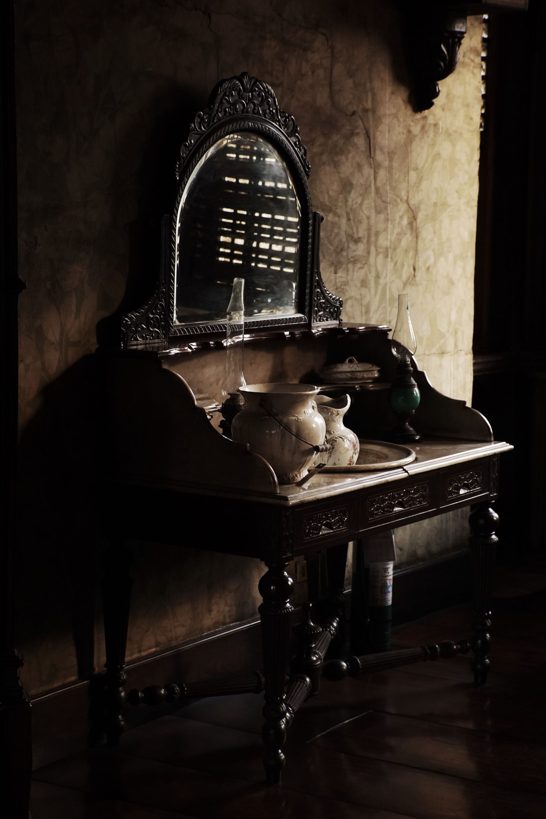 Carved dark timber washstand with an arched mirror, ceramic jug and basin