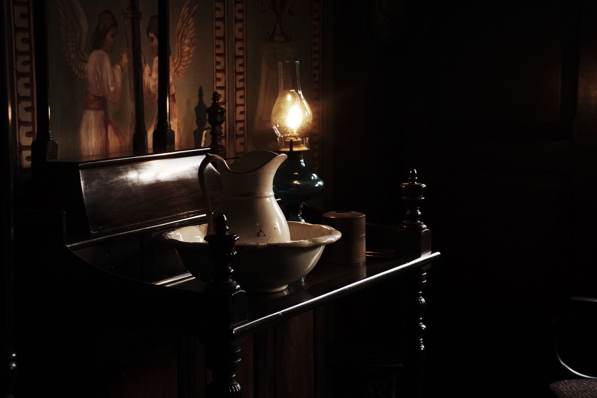 A dimly lit vintage room with lamp and wooden furniture