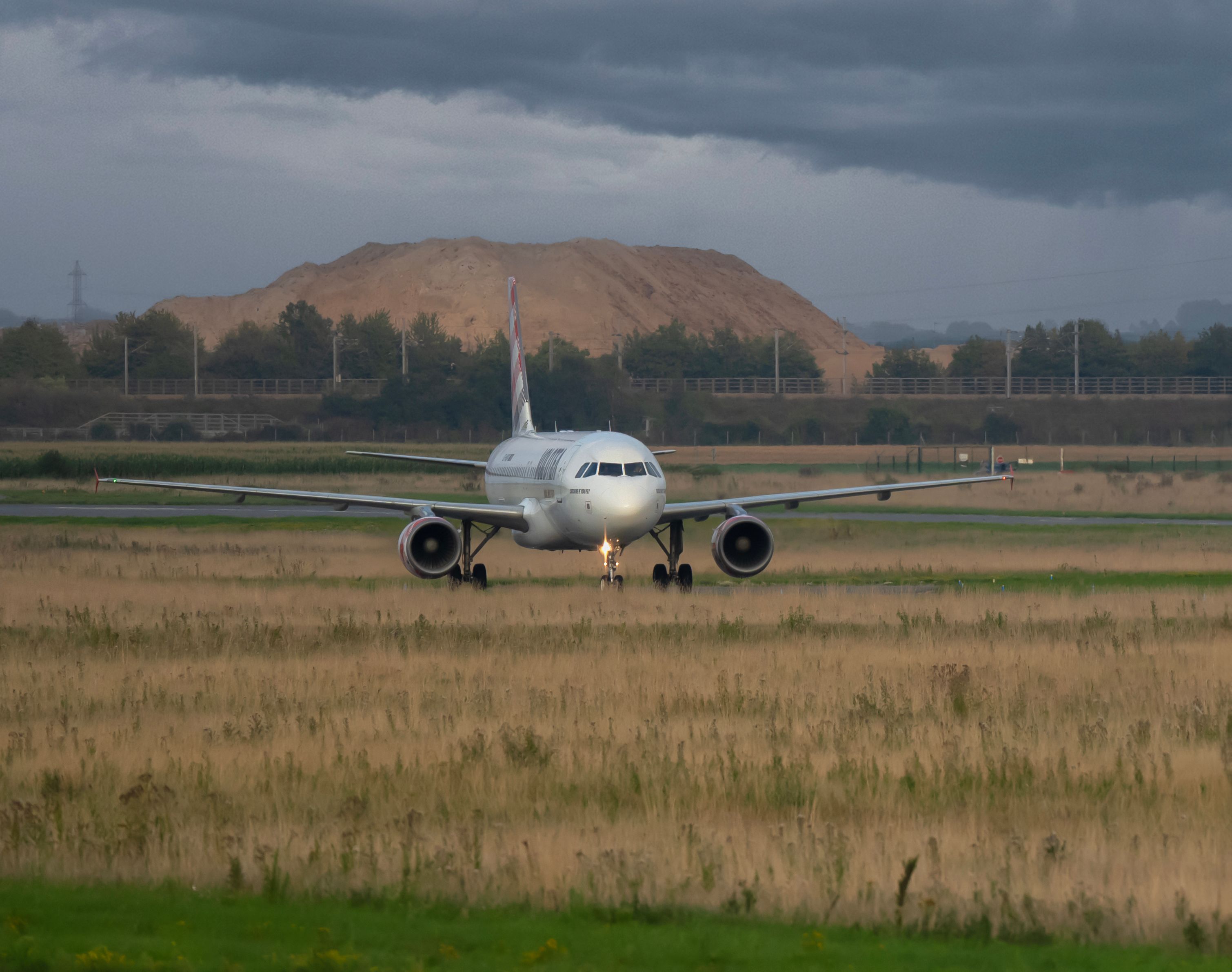 A commercial airplane preparing for takeoff on a scenic runway with mountains in the background. - Lille