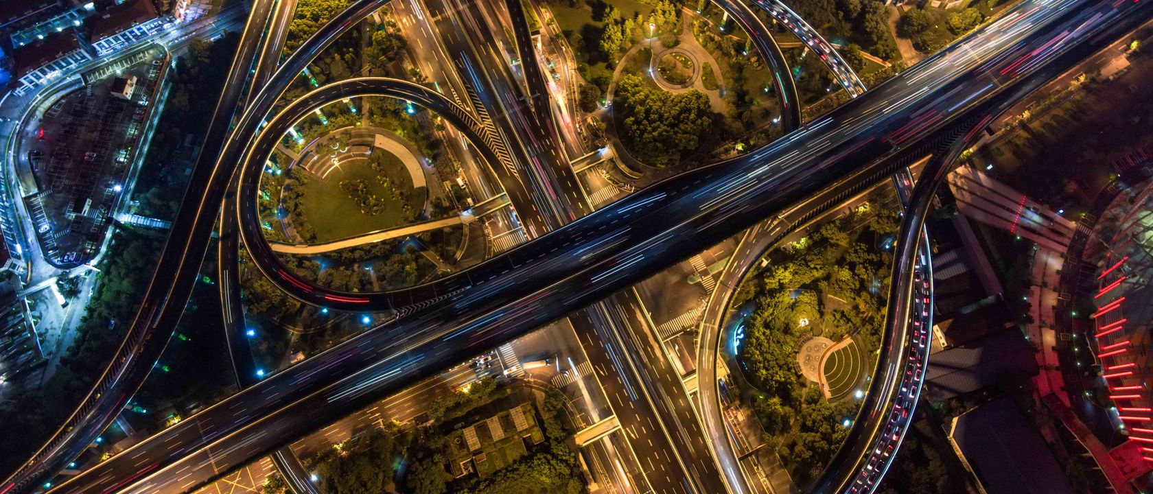 Stunning aerial view of intricate city highways and roundabouts illuminated at night.