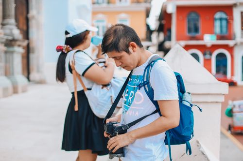 Free Man and woman exploring city streets with cameras, capturing vibrant urban life. Stock Photo