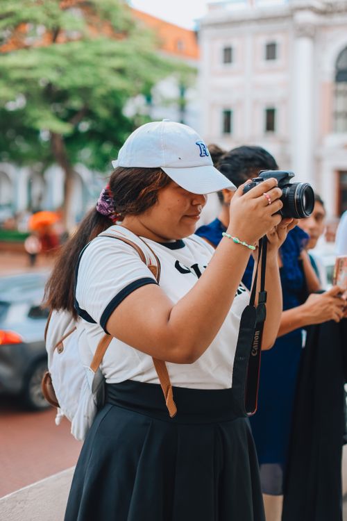 Free A young woman captures city scenery with her camera, showcasing urban exploration. Stock Photo