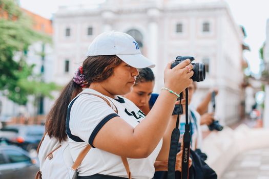 Young female photographer capturing a moment with a camera outdoors.
