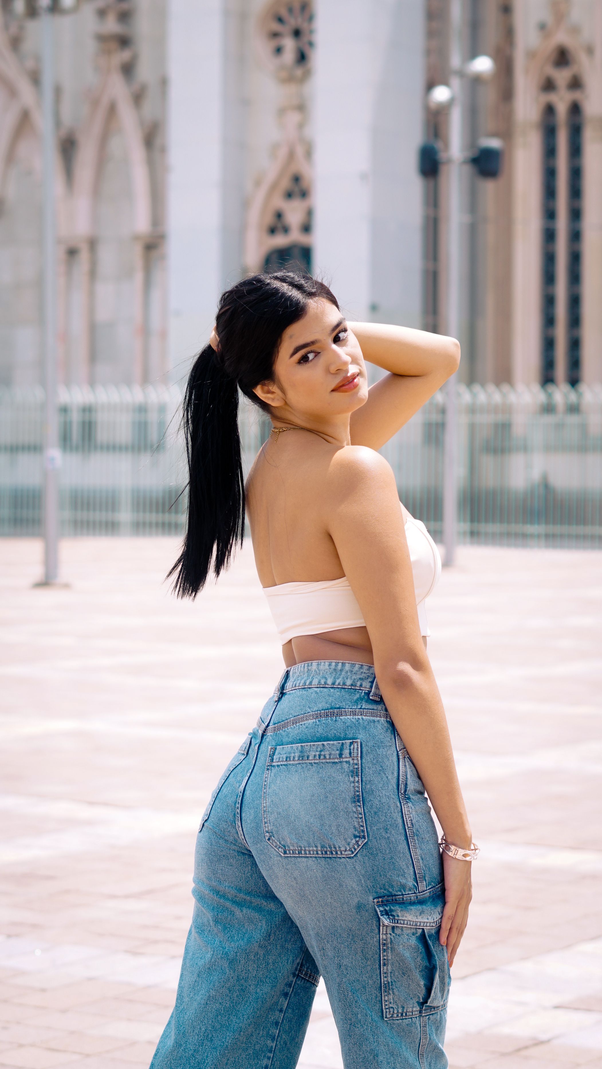 A woman in jeans and crop top posing confidently outdoors in León, Mexico.