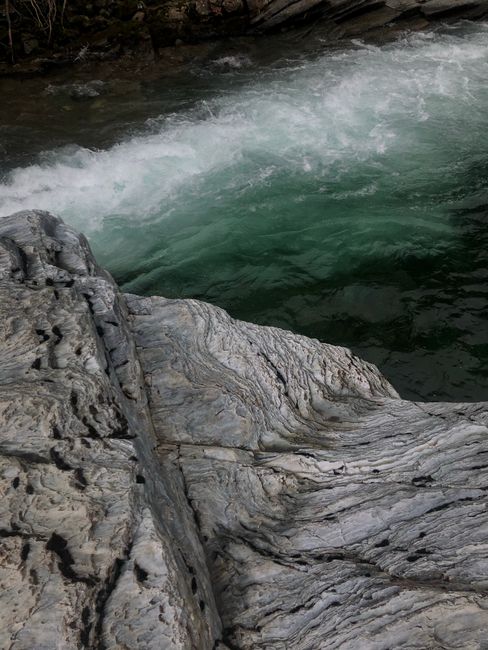 Close-up of a rugged cliff with bubbling, rough ocean waves in a dynamic seascape.