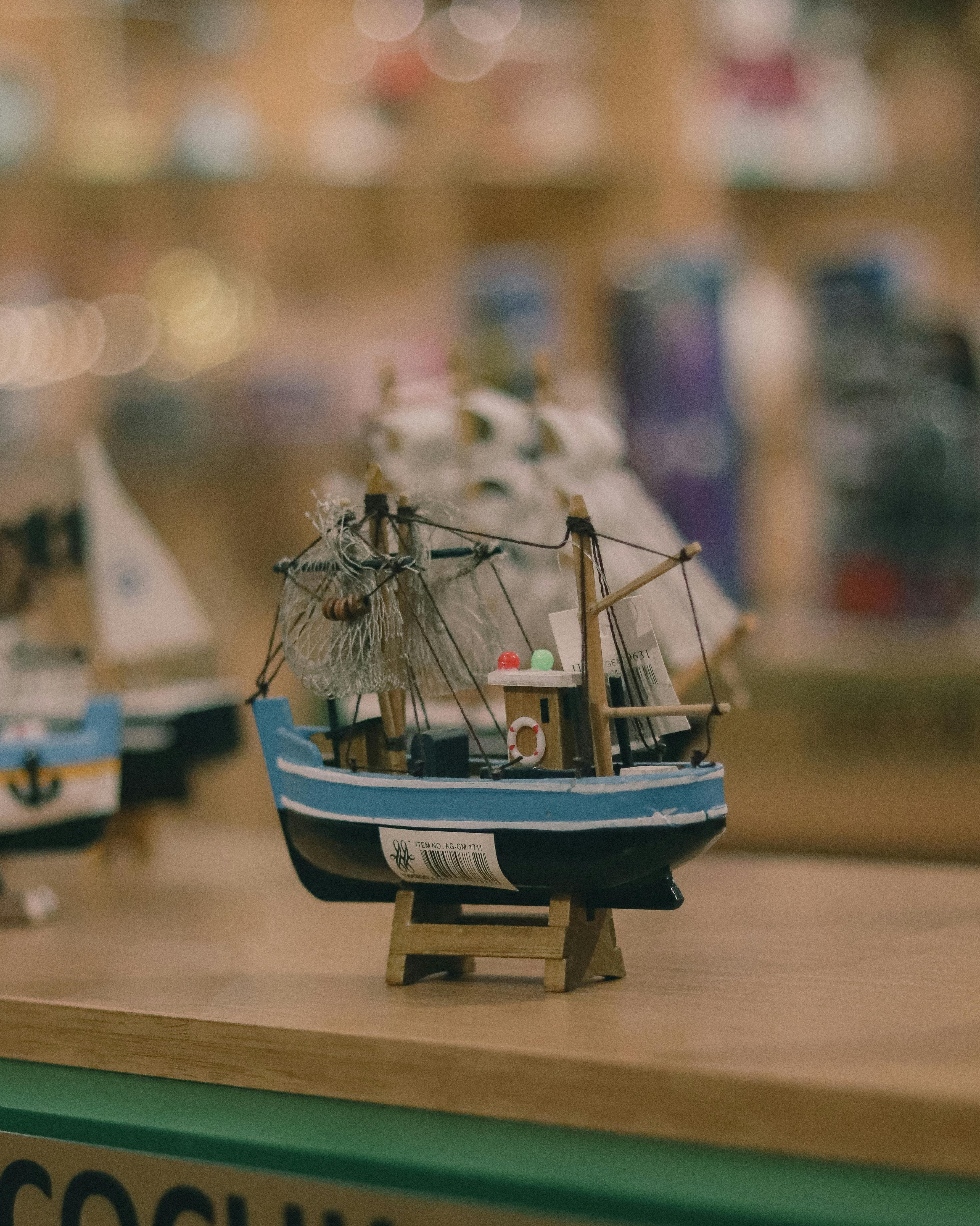 Free A miniature fishing boat model displayed on a shelf, evoking a nautical theme with selective focus and warm tones. Stock Photo