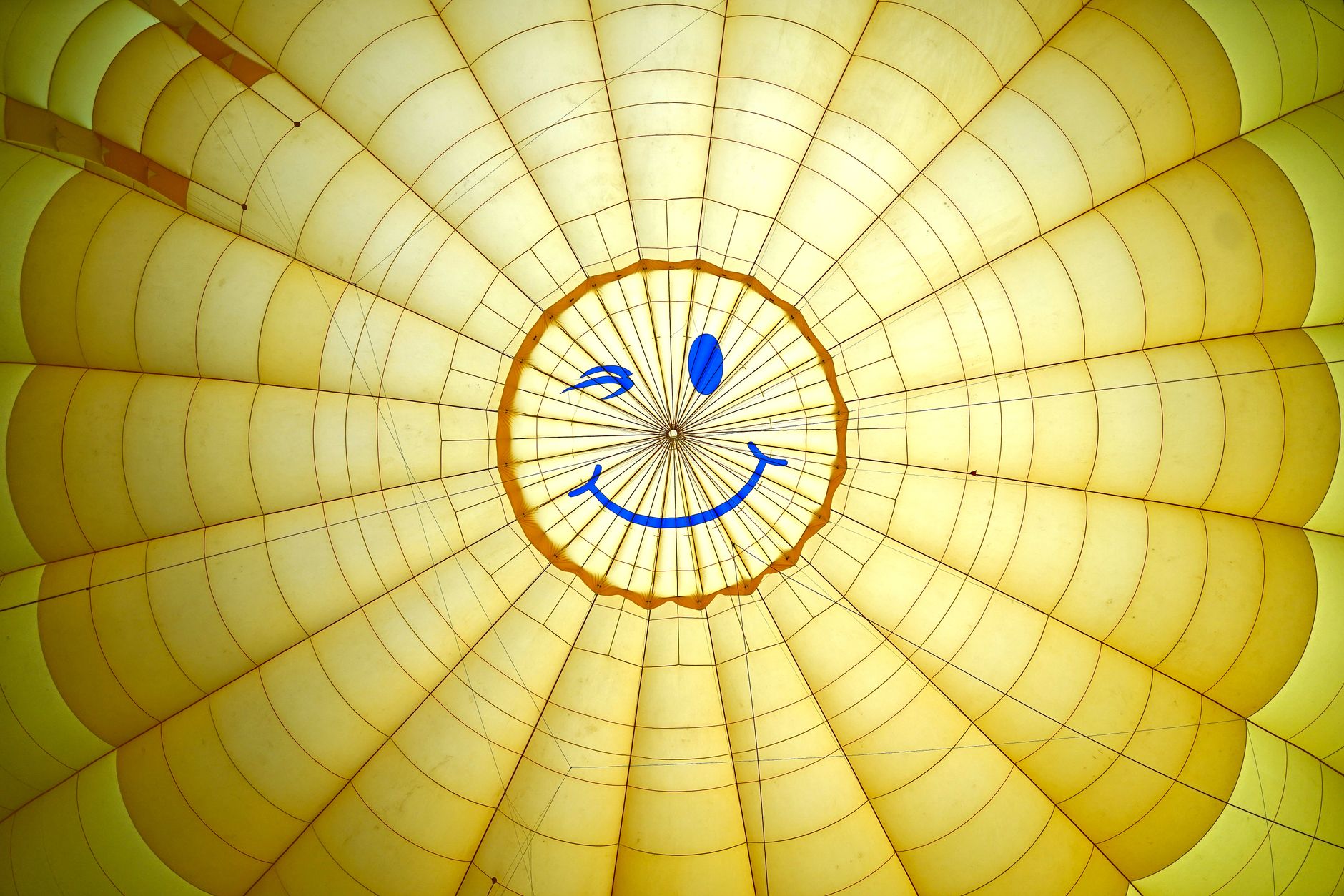 Inside view of a yellow hot air balloon with a bright blue smiley face design.