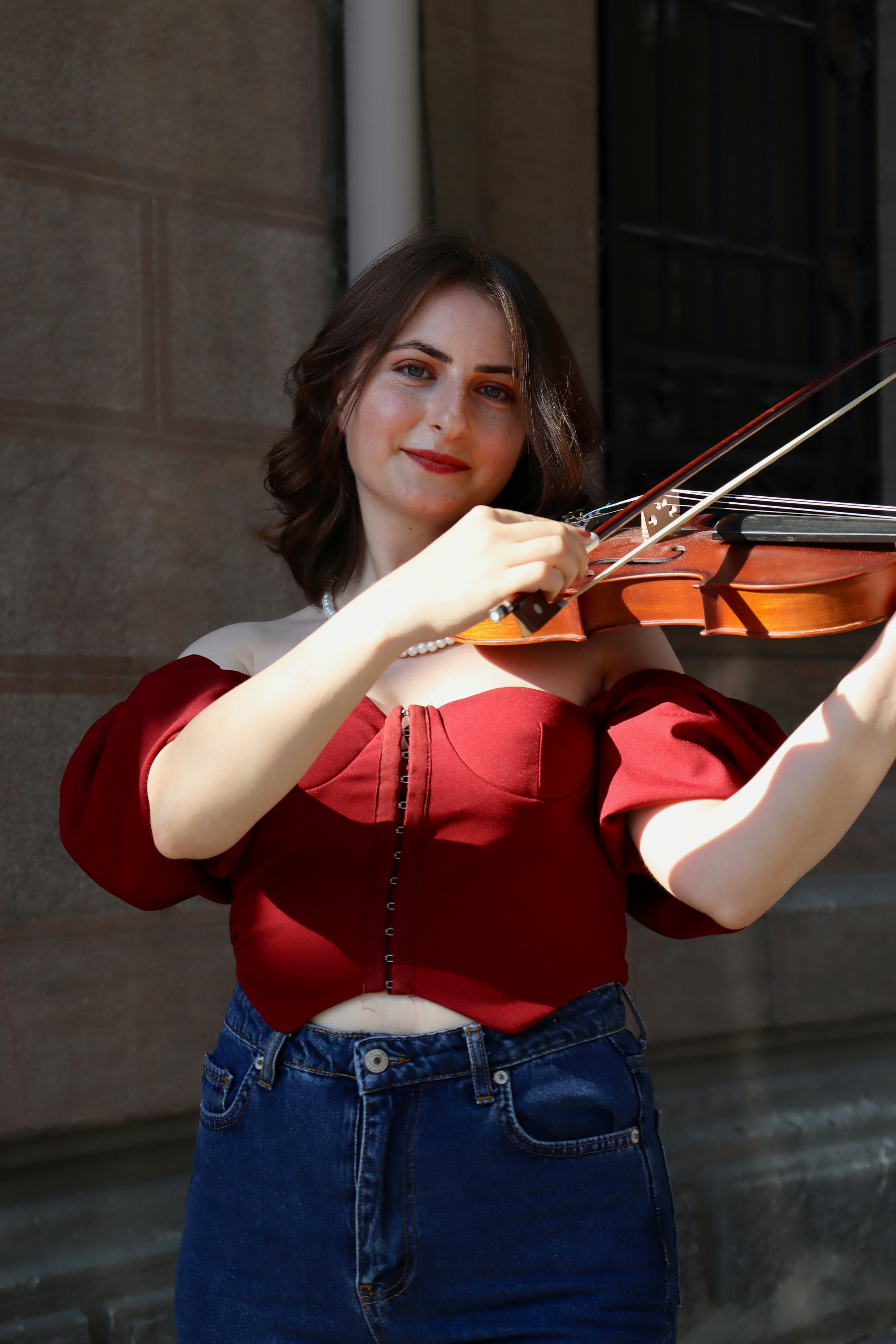 Young woman playing violin on a sunny street in Ankara, Türkiye.