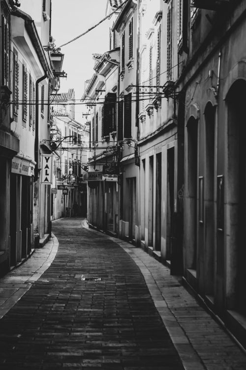 Free Explore the serene black and white urban alley in Koper, Slovenia. A quiet glimpse of European architecture. Stock Photo