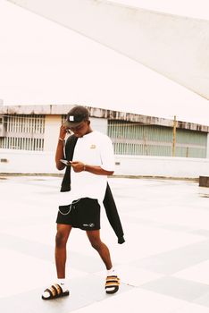 Man walking in urban setting, focused on smartphone. Modern city lifestyle captured outdoors.