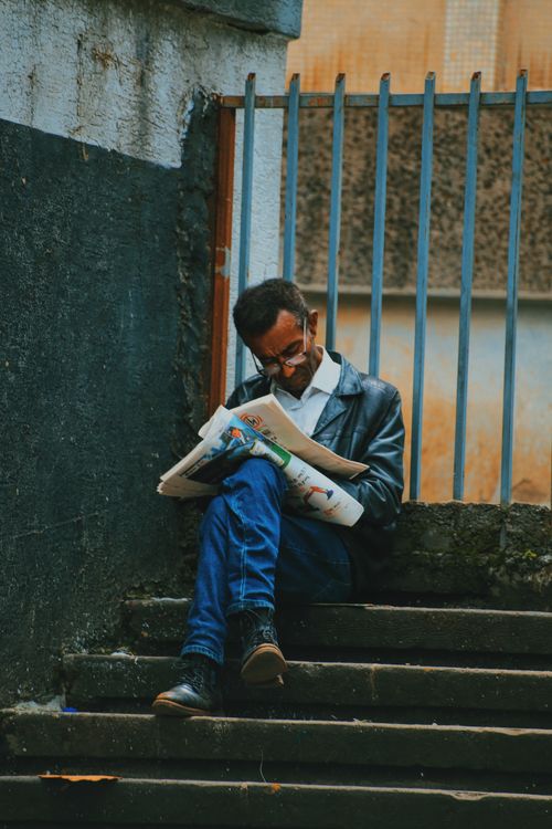 Free Adult man reading a newspaper while sitting on urban steps in Addis Ababa, Ethiopia. Stock Photo