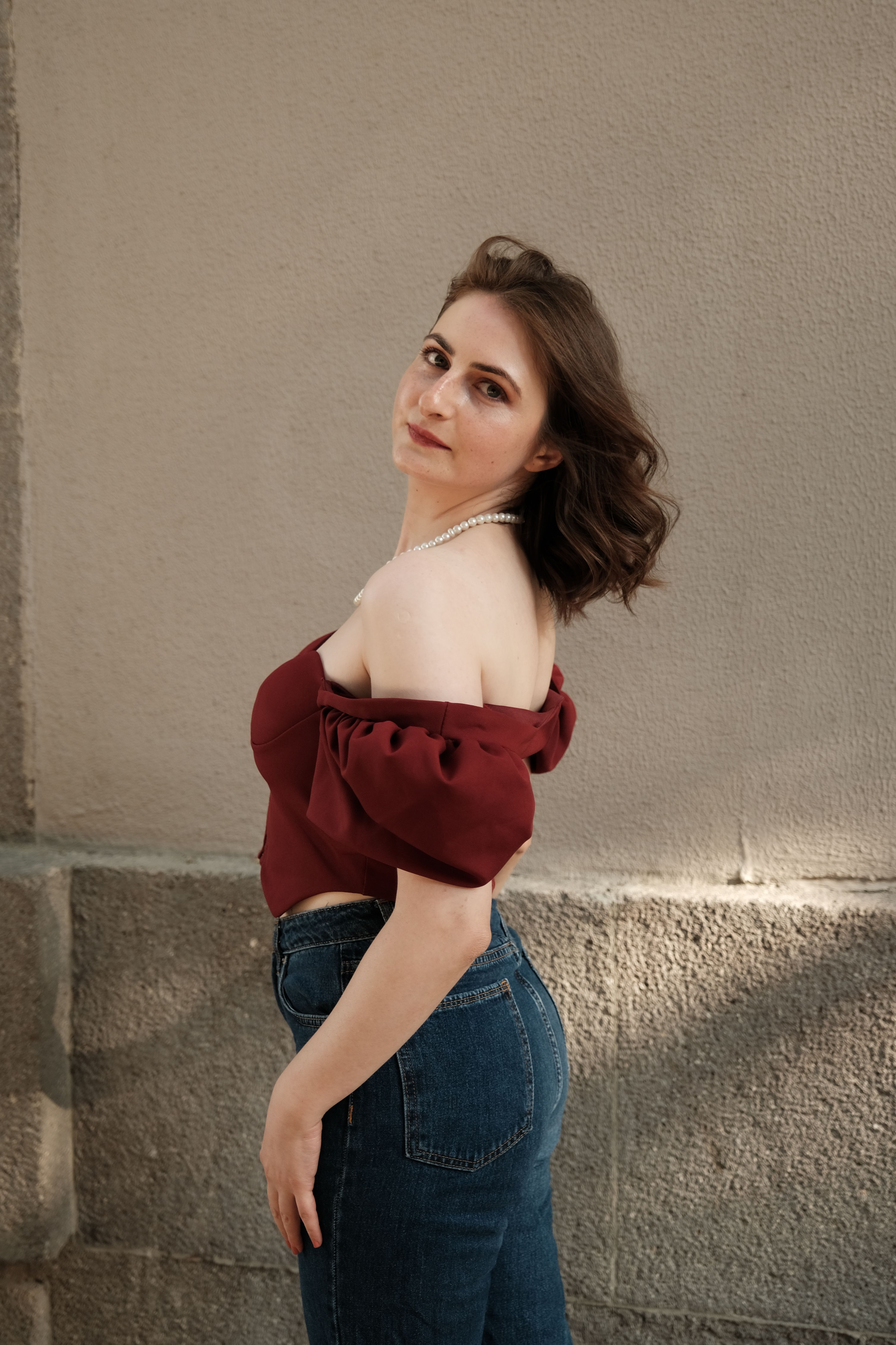 woman in burgundy wrap top and dark wash jeans