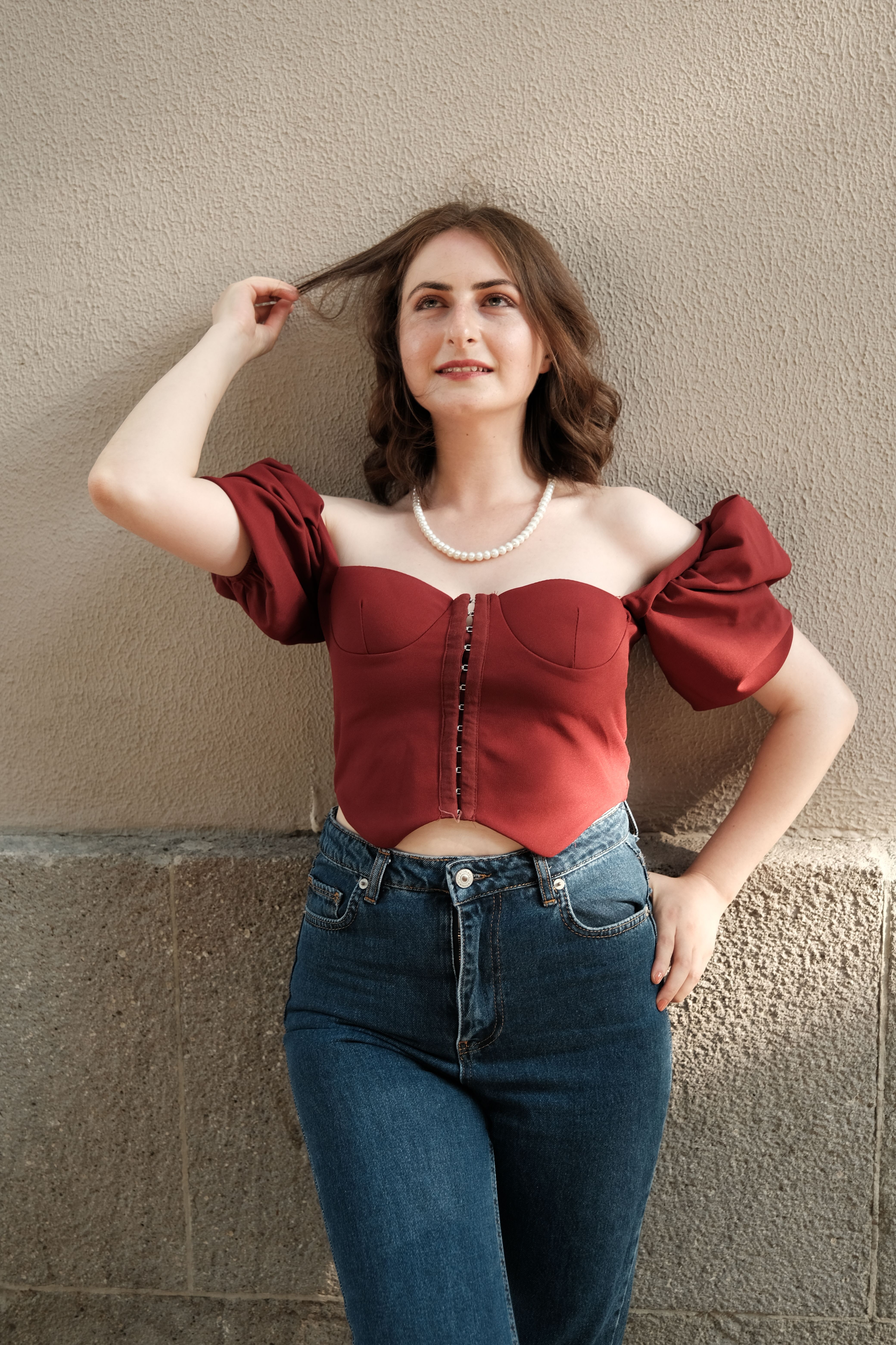 Woman in light wash jeans with a red off-shoulder top