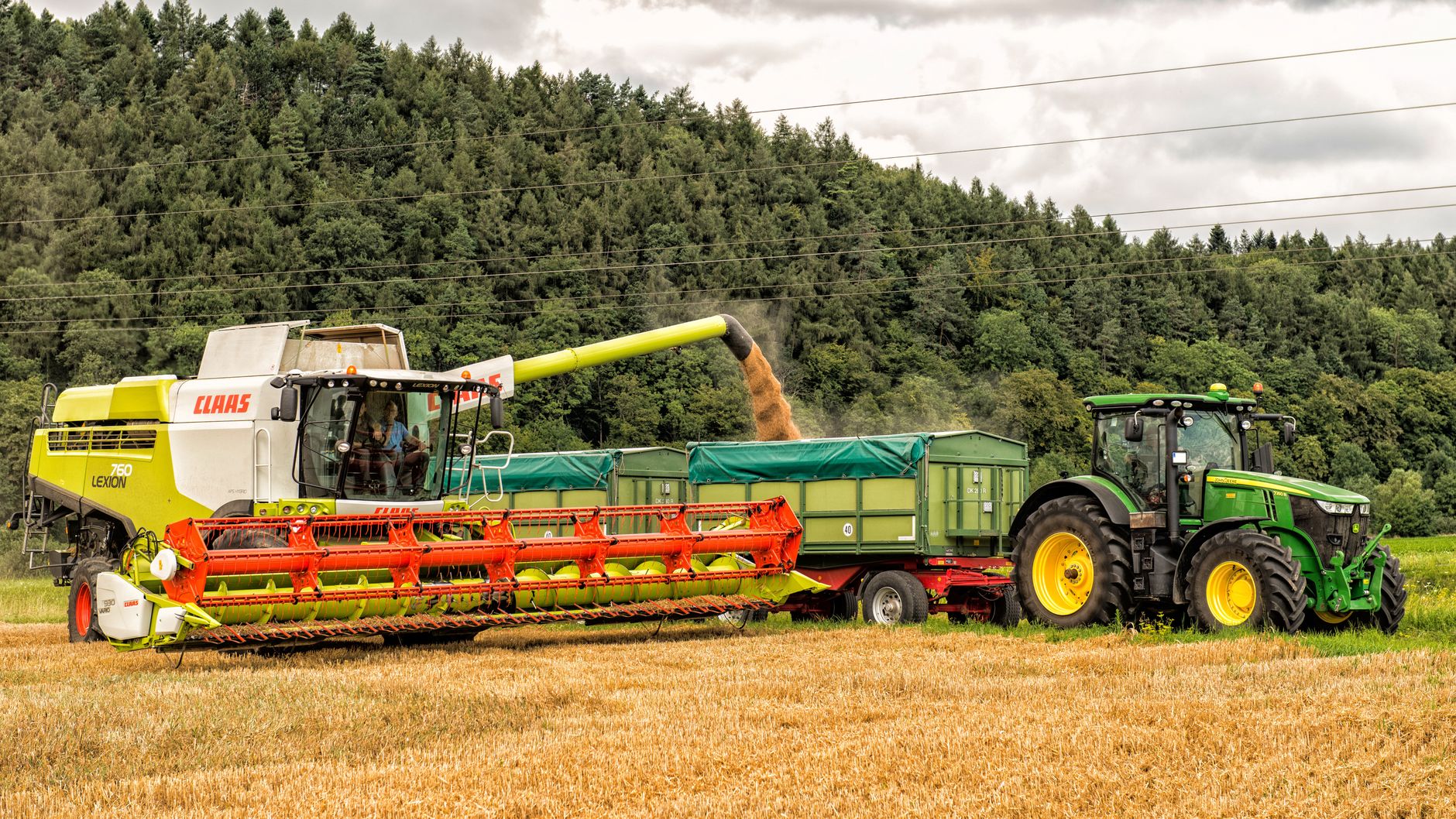 Combine harvester unloading grain into trailer in rural Höxter, Germany.