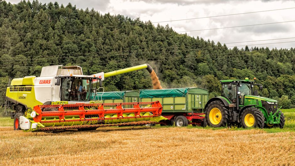 Combine harvester unloading grain into trailer in rural Höxter, Germany.