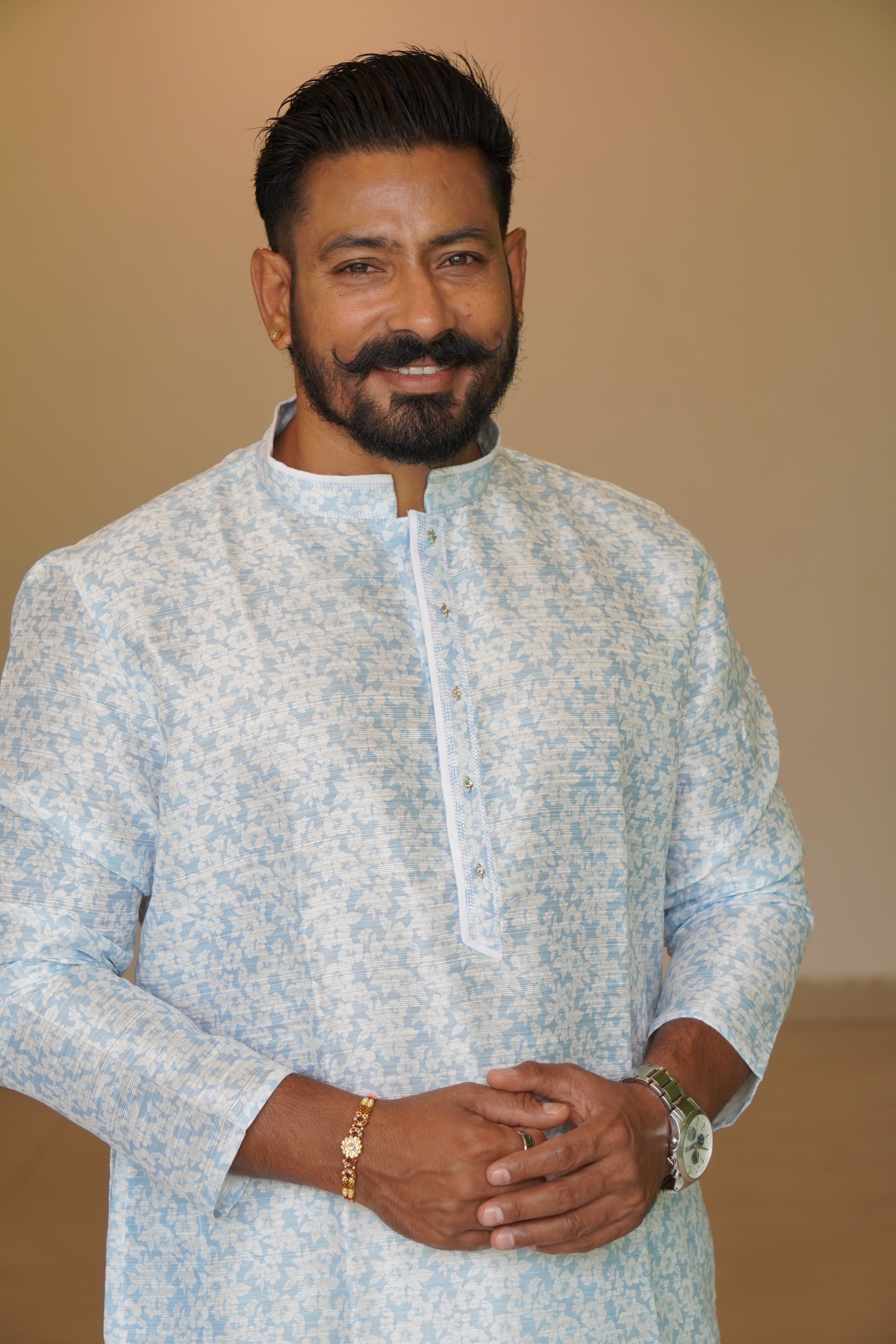 Smiling man wearing a light blue patterned kurta, showcasing cultural fashion.