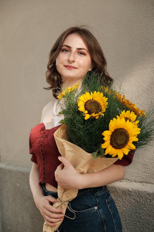 Young Woman Holding a Bunch of Sunflowers and Smiling 