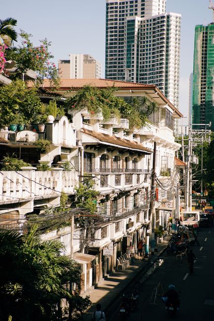Charming historic building amid Manila's modern skyline, capturing urban contrast.
