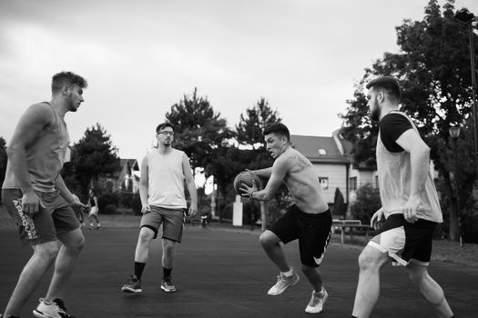 Group of young men playing basketball outdoors, showcasing teamwork and competition.