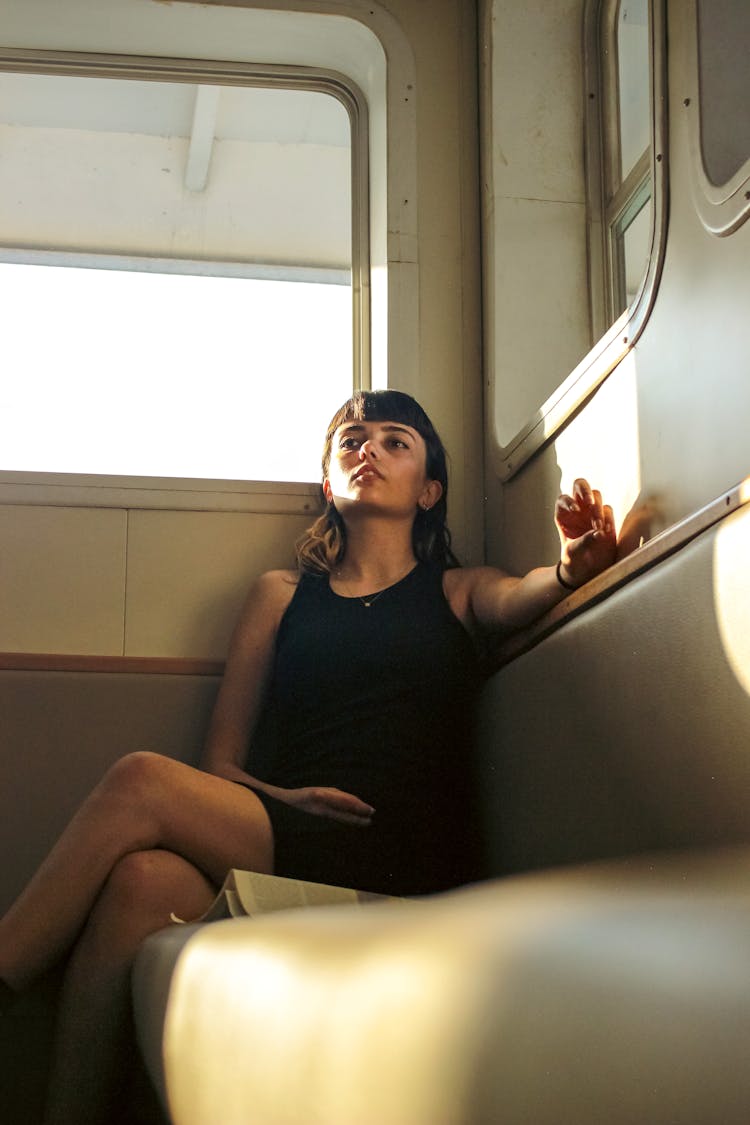 Young Brunette Woman In Black Mini Dress Sitting On A Sofa