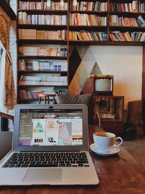 Laptop and Coffee Cup Standing on a Cafe Table