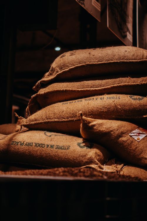 Free A close-up shot of stacked burlap sacks in an indoor warehouse setting. Stock Photo
