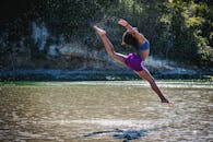 年轻女子在河边跳跃，展现出灵活与活力