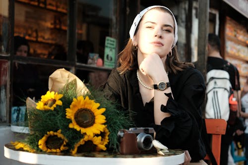 Woman in a Headscarf Sitting by a Table with Sunflowers