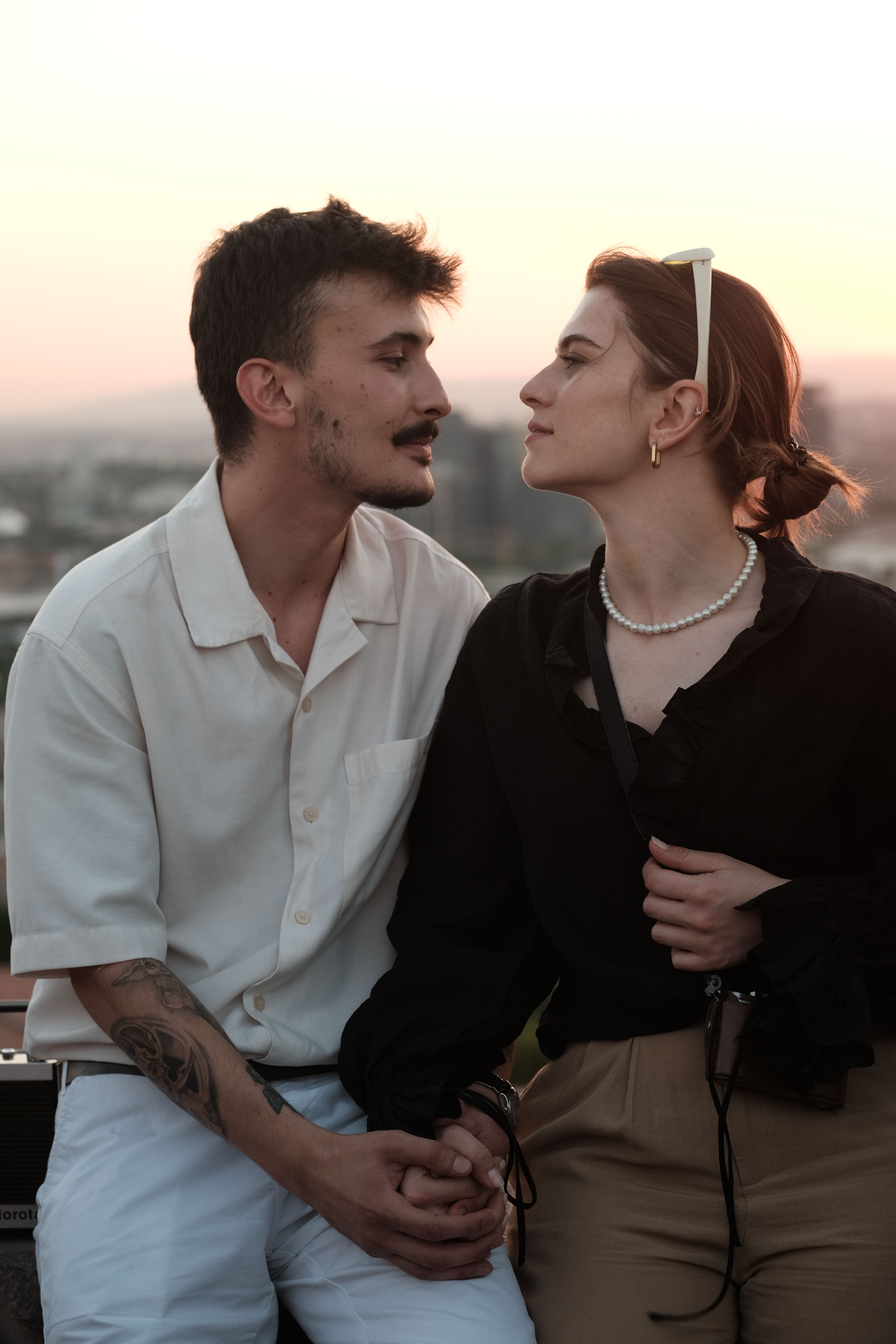 Young couple sharing a tender moment during sunset, holding hands and looking into each other's eyes.