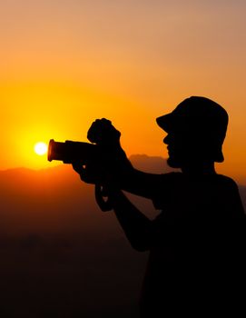 A silhouette of a photographer capturing the sunset, showcasing creative moments.