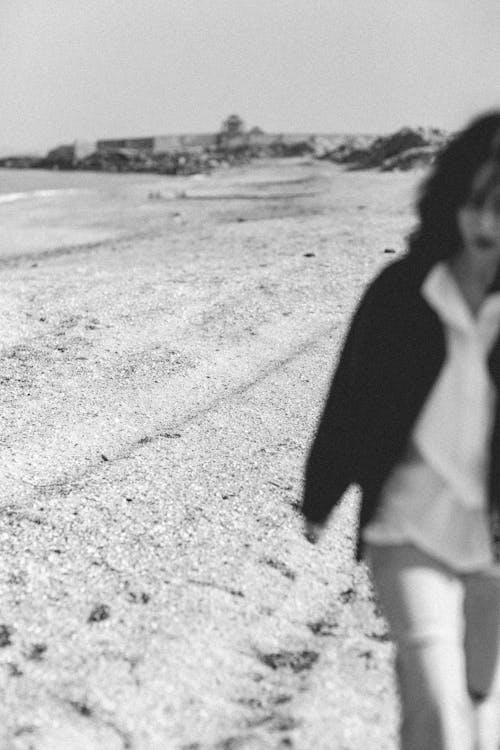 Black and White Photo of a Woman Walking on a Beach