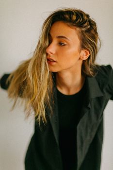 Fashionable woman with blonde hair and black attire posing against a neutral backdrop.