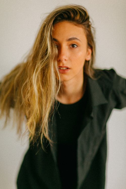 Free A young woman with long blonde hair wearing a black shirt poses against a white background. Stock Photo